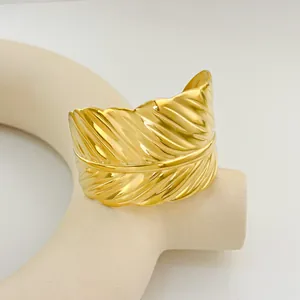 Detailed close-up of a wide golden feather cuff bracelet with intricate textured patterns
