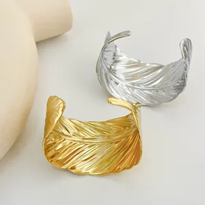 Detailed view of wide feather-textured open bangles in polished gold and silver steel