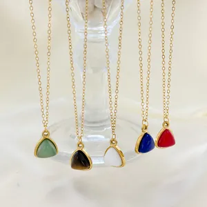 Minimalist gold necklaces with colorful triangle pendants on silk background