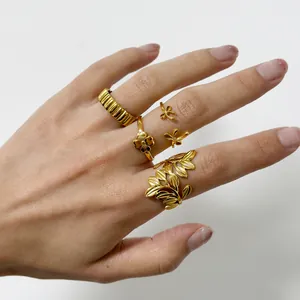 Detail of four 18k gold-plated rings including ribbed band and floral leaf patterns