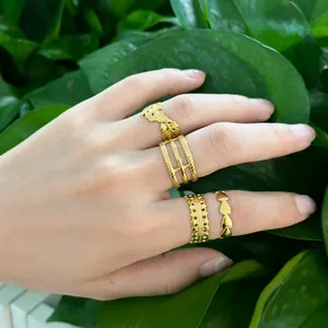 Detail of gold stainless steel ring set featuring leaf patterns and layered bands on a hand