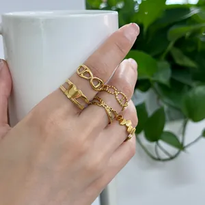 Detail of 18K gold plated ring set featuring heart and chain textures on female model