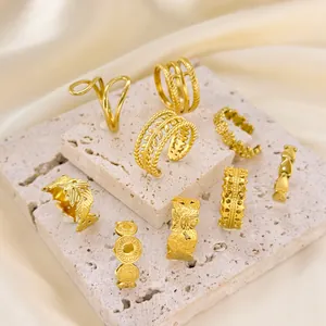 Collection of various gold-plated stainless steel rings displayed on stone props