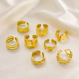 Set mit acht goldenen Edelstahlringen mit verschiedenen Texturen auf weißer Seide