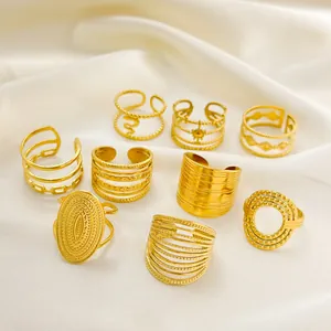 Dettaglio di 9 anelli in acciaio al titanio placcati oro con texture intrecciate e geometriche