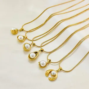 Elegante collana in titanio dorato con vari pendenti di perle su sfondo di seta