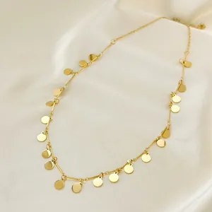 Minimalist gold plated sequin necklace with circular pendants on white silk background