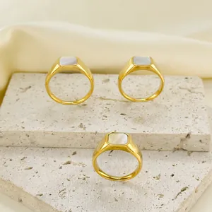 Drei goldene Edelstahlringe mit quadratischen Perlmutt-Inlays auf steinerner Kulisse