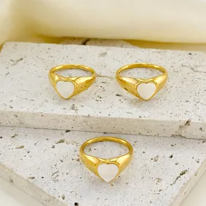 Three 18k gold plated heart rings with white shell inlay on stone and fabric background