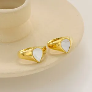 Golden teardrop signet ring set with white mother of pearl inlay on ceramic tray