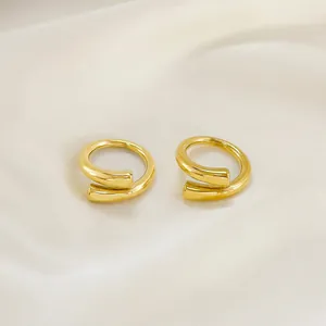 Pair of minimalist golden spiral open rings with polished finish on silk background