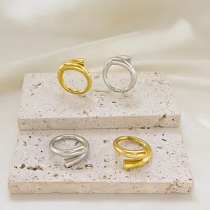 Minimalist entwined open rings in gold and silver finish on stone display stands