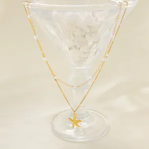 Double-layered gold starfish pendant necklace with white pearls on elegant beige satin