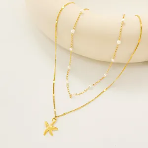 Double-layered gold necklace with starfish pendant and white pearls on white background