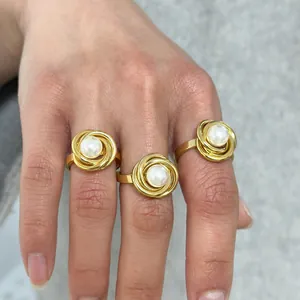 Detailansicht von drei 18K vergoldeten Spiralringen mit weißen Perlen an der Frauenhand