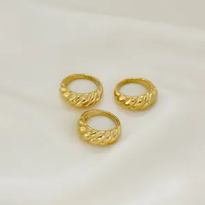 Three gold twisted croissant dome rings in polished stainless steel on silk fabric