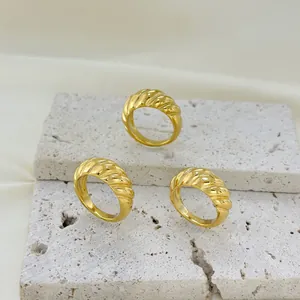 Elegant gold-plated croissant twisted rings on travertine stone base with textured fabric
