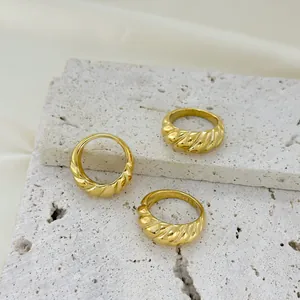 Polished gold stainless steel twisted horn rings set on beige stone platform