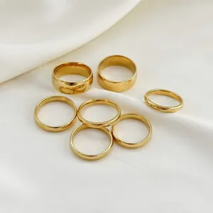 Set of seven minimalist 18k gold plated stainless steel rings on white silk fabric