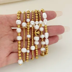 Detail of 18K gold beaded bracelets and natural pearls set with a floral crown charm