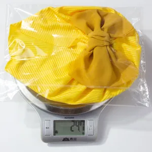 Gros plan d'un turban jaune pour bébé avec nœud, affichant 24,7g sur la balance