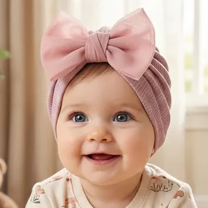 Gros plan du bonnet turban rose pour bébé avec un grand nœud en résille sur un nourrisson