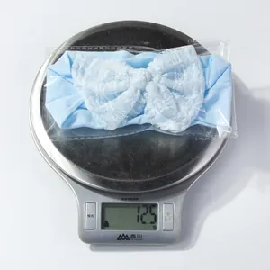 Close-up of a soft blue nylon baby headband with a white lace bow on a digital scale