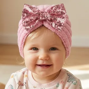 Détail du bonnet turban rose pour bébé avec un grand nœud en paillettes étincelantes