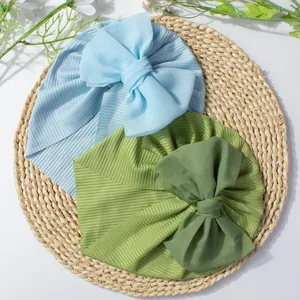 Détail de bonnets pour bébé en tricot côtelé bleu et vert avec grands nœuds en mousseline