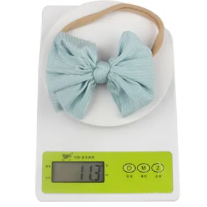 Gros plan d'un bandeau bébé bleu clair à nœud nervuré pesant 11,3 g sur une balance