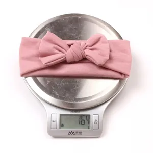 Lightweight pink baby bow headband weighing 16.4g displayed on a precision digital scale
