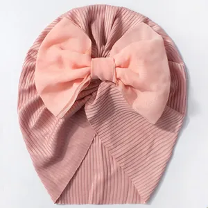 Détail du bonnet pour bébé en maille côtelée avec un grand nœud en organza rose tendre