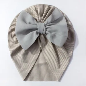 Détail du bonnet turban pour bébé en maille côtelée champagne avec nœud en mousseline grise