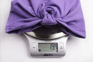 Detail shot of a purple bohemian baby turban on a scale showing a lightweight of 19.4g
