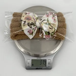 Bandeau bébé tricoté marron avec nœud floral pesant 31,9g sur une balance de cuisine