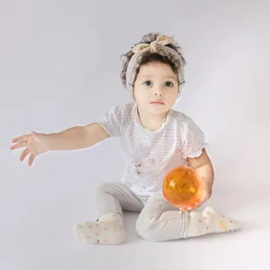 Knitted baby headband in cream white featuring a floral bunny ear bow on a young model