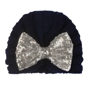 Gros plan du turban tricoté bleu marine pour bébé avec un grand nœud en paillettes argentées