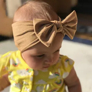 Detail of khaki baby headband with large bow in soft knit fabric on infant