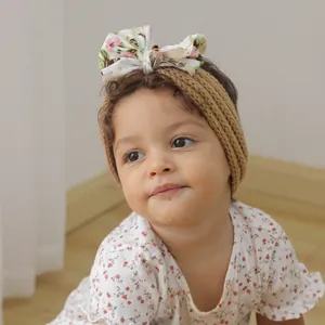 Gros plan d'un bandeau pour bébé en tricot marron orné d'un nœud à motif floral doux