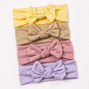 Set of four soft elastic baby headbands with handmade bows in yellow, pink and lilac