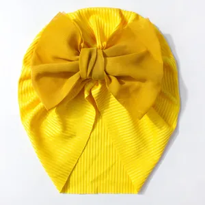 Gros plan détaillé du bonnet turban jaune pour bébé avec un grand nœud décoratif