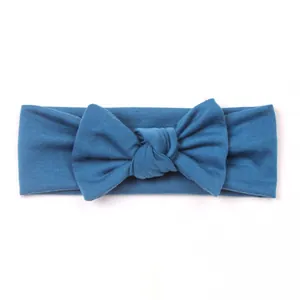 Detail view of teal knitted baby headband with a handmade bow and soft ribbed texture