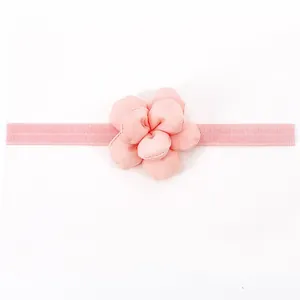 Dettaglio del fiore di camelia in tessuto rosa e fascia elastica per neonata