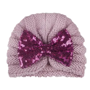 Détail du bonnet tricoté pour bébé avec gros nœud en paillettes fuchsia