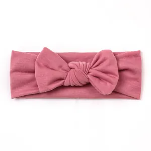 Detailed shot of soft knitted pink baby headband featuring a large tied bow
