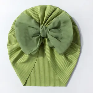 Détail du bonnet turban pour bébé en tissu côtelé vert avec un grand nœud en mousseline