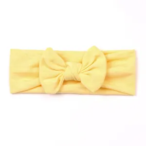 Soft light yellow baby headband with decorative knotted bow on a white background