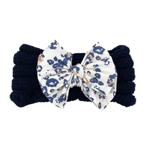 Détail du bandeau tricoté bleu marine pour bébé avec un grand nœud à motif léopard