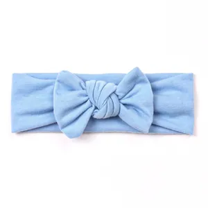 Close-up of soft light blue knitted baby headband with a large knotted bow detail