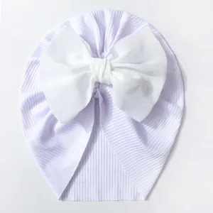 Détail d'un bonnet bébé en maille côtelée lilas avec un grand nœud décoratif blanc